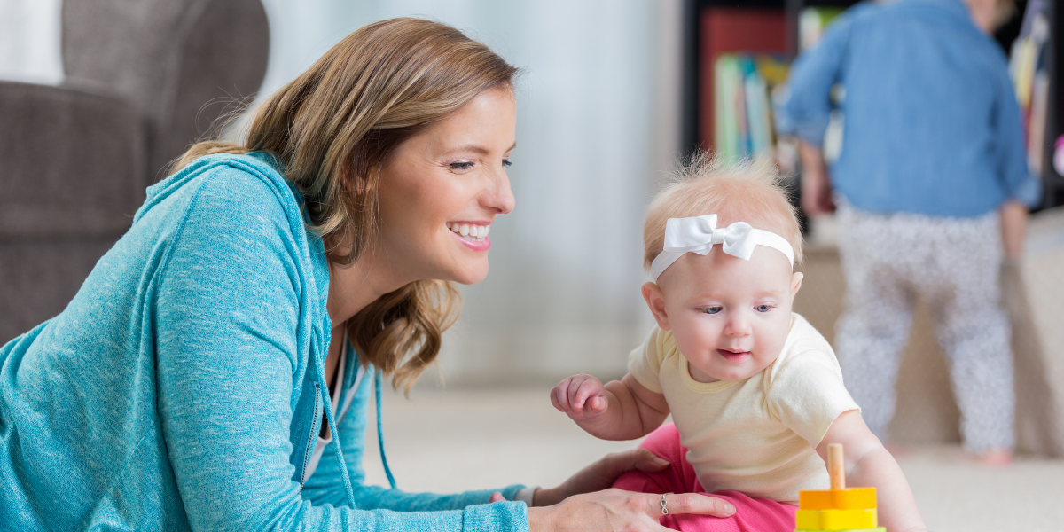 Nanny playing with baby on floor